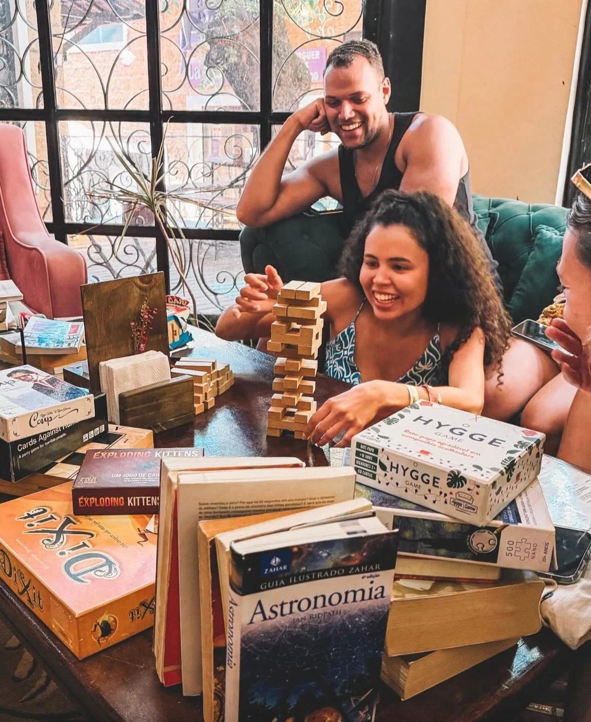 Clientes jogando jogos de tabuleiro em uma mesa com livros no salão do Hygge