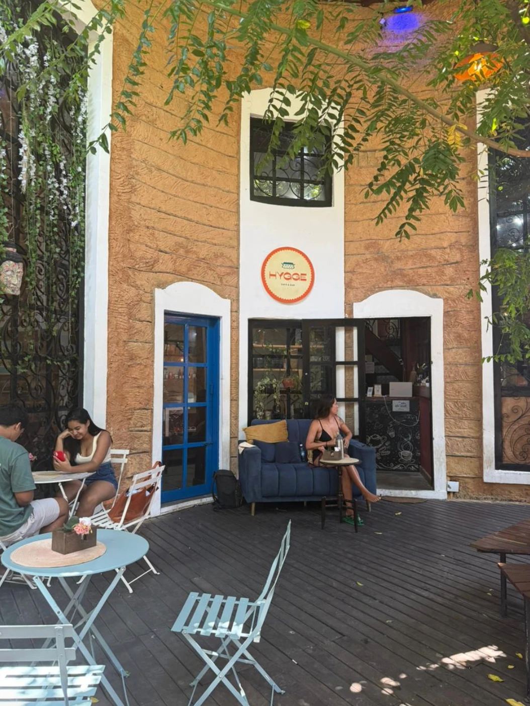 Fachada do Hygge na Galeria Pipa Mar, com o logo na parede, sofá azul e mesas no deck externo